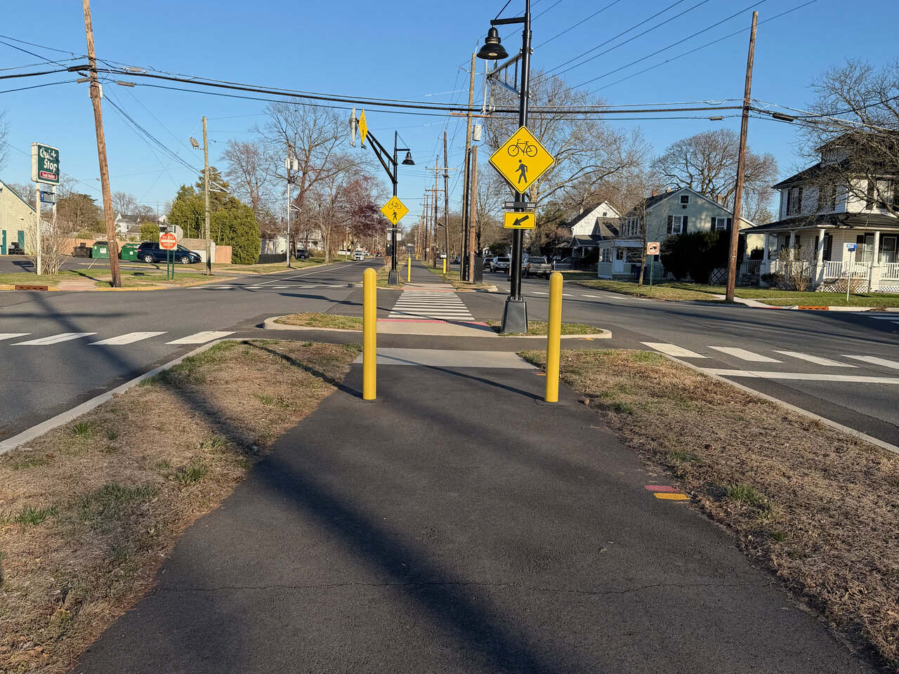 Modern 5th Street Rail Trail with paved asphalt path, yellow safety bollards, and pedestrian crossing signs